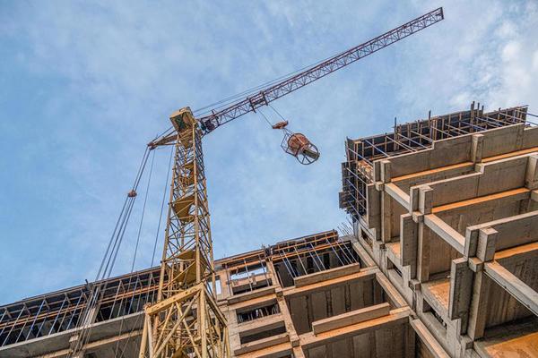 a-low-angle-shot-of-a-crane-with-equipment-on-a-construction-site-with-a-new-building-infrastructure-pouring-concrete-into-a-mold-photo